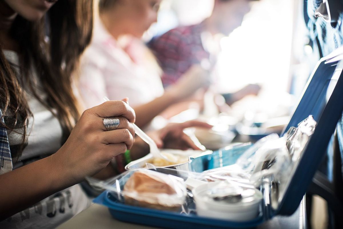 飛行機の機内食を食べる人