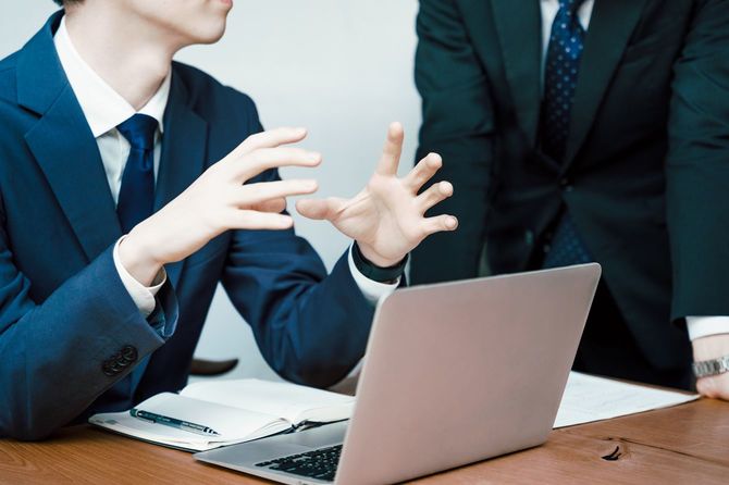 スーツを着て仕事をしながら話す2人の男性