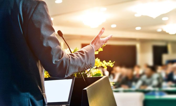 会議場で聴衆の前で演説をするビジネスマン