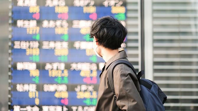 市況情報をみて足を止めた若い男性