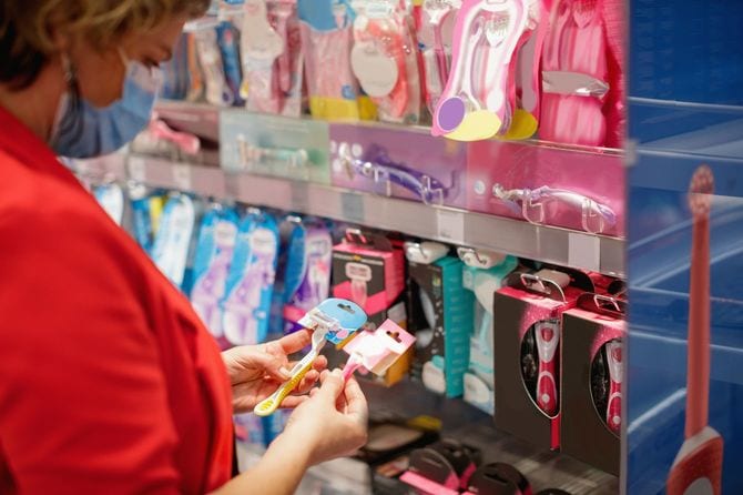 スーパーの棚でカミソリを比較する女性