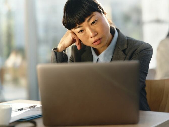 PCを前に気だるげなビジネスウーマン