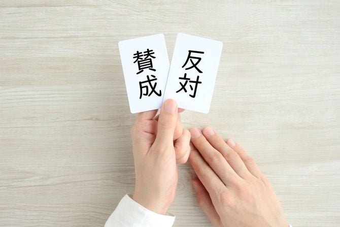 賛成と反対と書かれた2枚のカードを持つ手元