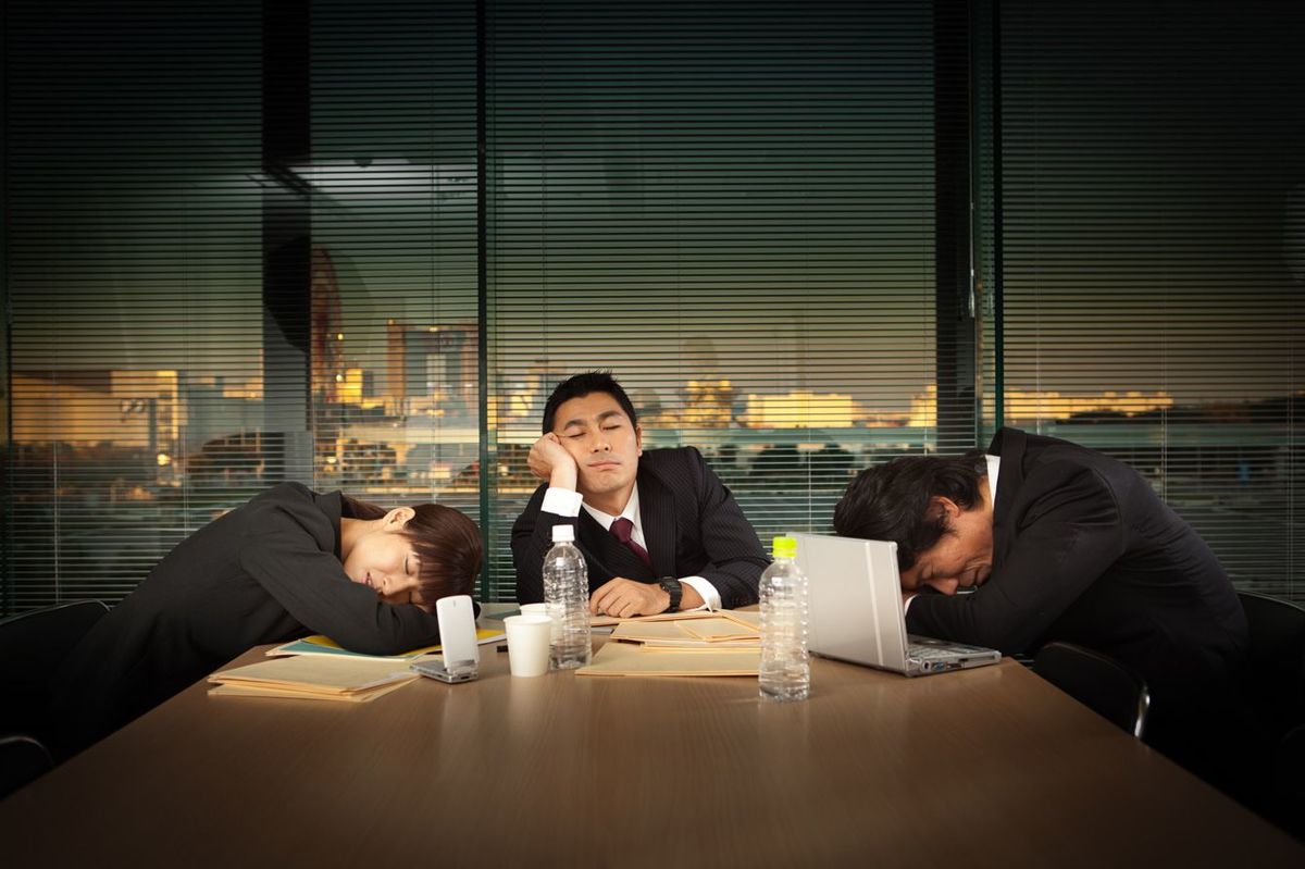 暗いオフィスの中で疲れてぐったりしたビジネスマンたち