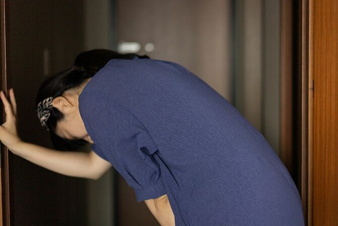 体調の悪い女性が戸口でうずくまっている