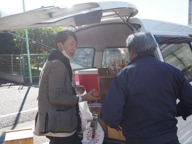 リンゴを手にお客さんと話す片山さん