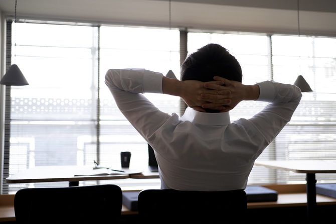 手を後頭部で組んで一息つくアジア人ビジネスマン