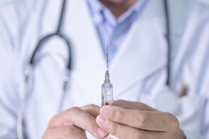 注射を持つ男性医師の手元
