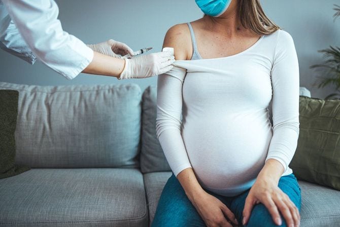 若い妊婦にワクチンを打つ女性医師