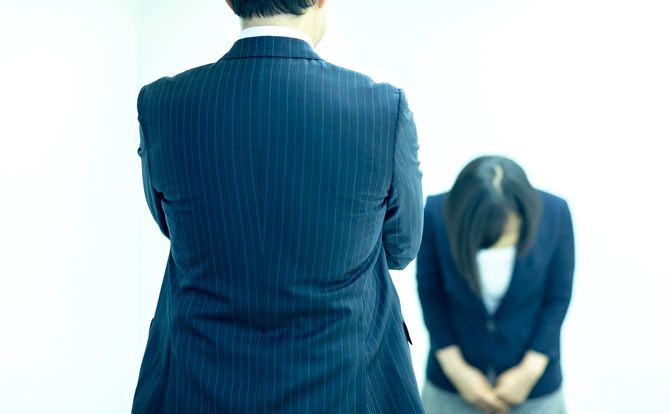 頭を下げる女性社員と腕を組む男性社員