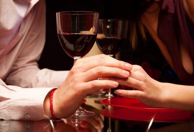 ワイングラスが置いてあるすぐ近くで手をつなごうとしている男女