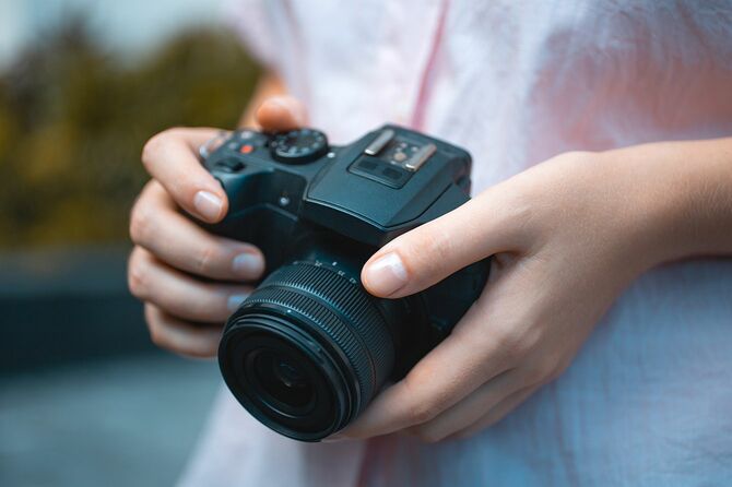 写真家がデジタルカメラを手に持ち、ピントを合わせ、写真を撮る