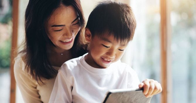 タブレット端末を使用している息子を笑顔で見守る母親