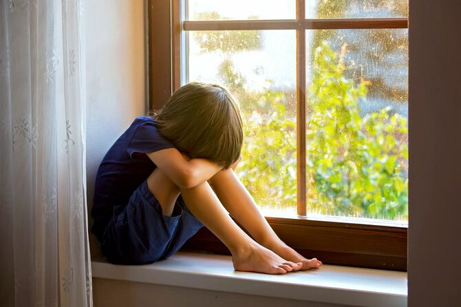 出窓の前に座って落ち込む男の子