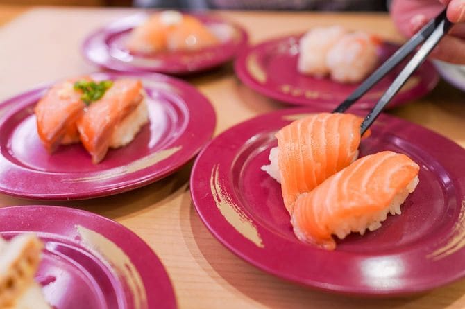 回転寿司でサーモン寿司を食べようとしている人の手元