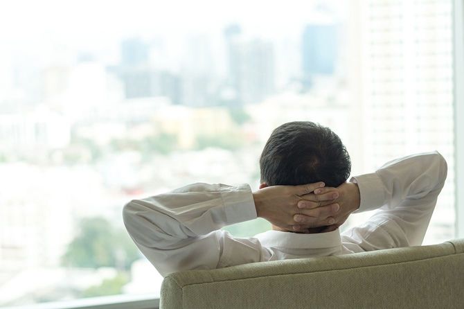 頭の後ろで手を組んで椅子に座っているビジネスマン