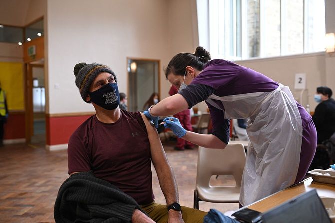 英中部シェフィールドで新型コロナウイルスのワクチン接種を受ける男性（左）