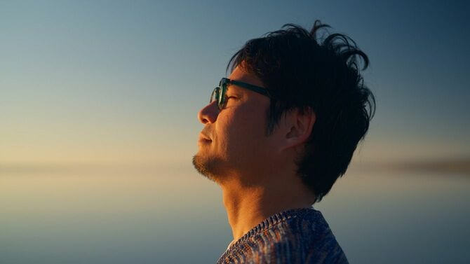 自然の中で目を閉じる男性