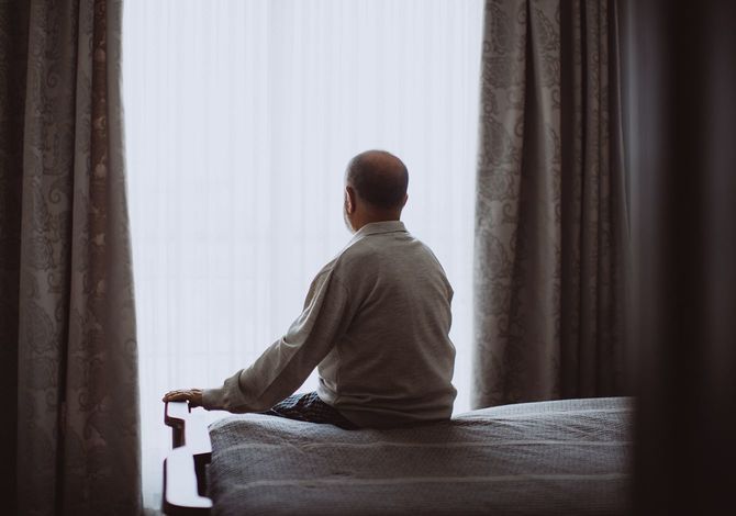 自宅でベッドに座っているうつ病の先輩のショット