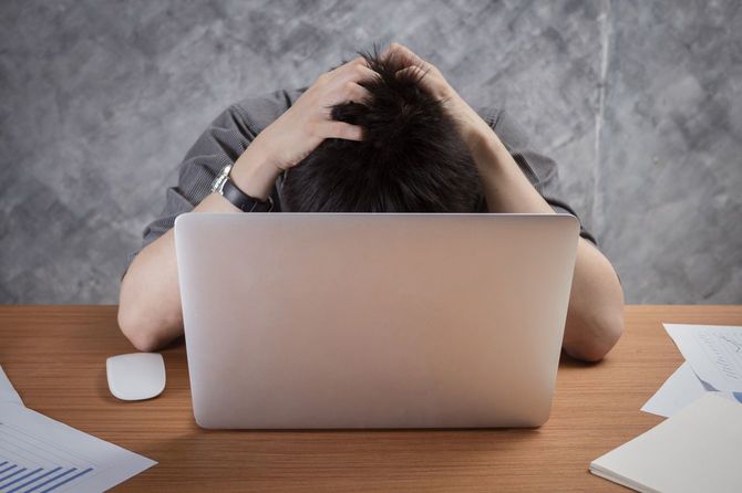 パソコンの前で頭をかきむしる男性