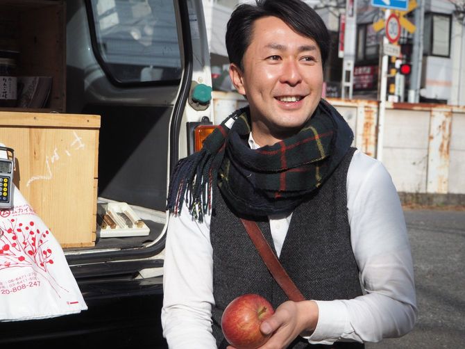 赤いリンゴを持ちチェックのマフラーを巻いた片山さん