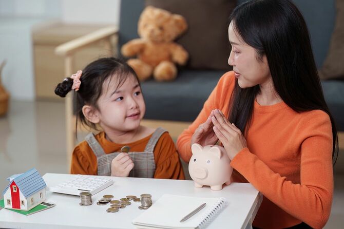 親子が貯金箱を使って貯金について話し合っています