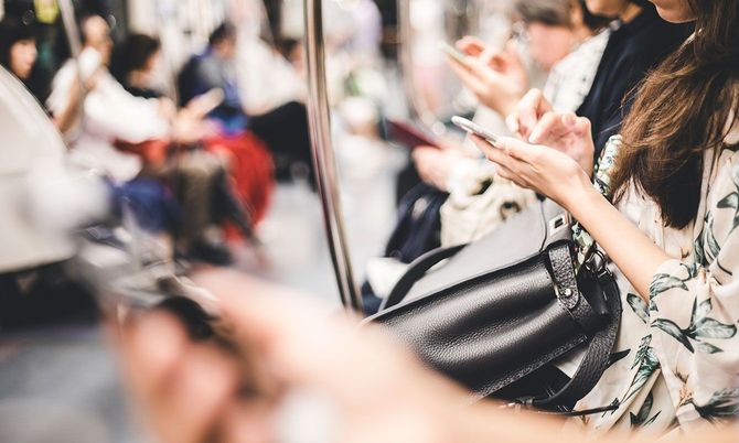 電車の中でスマホを見ている人々