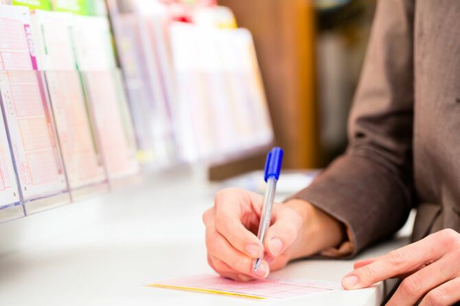 宝くじの用紙に記入している女性の手元