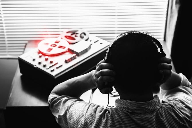 テープレコーダーの音声をヘッドフォンで聴く男性