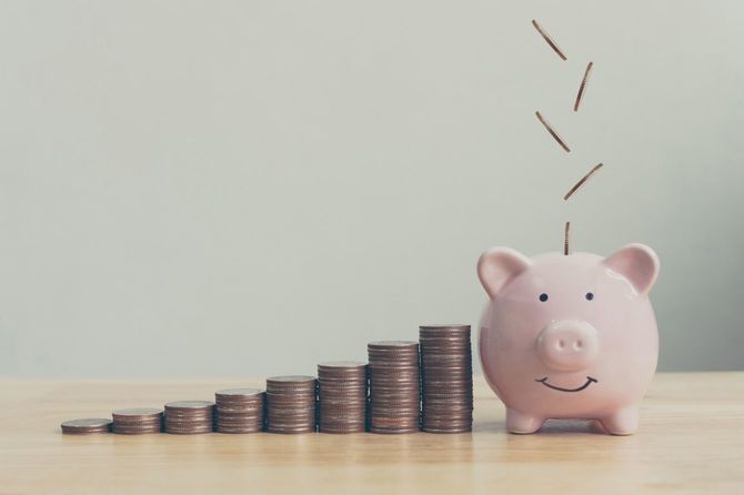 硬貨を入れられる豚の貯金箱と、その横に階段状に積み上げられた硬貨