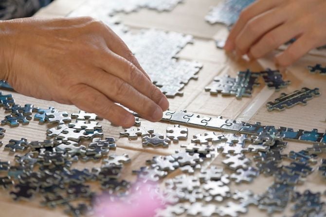 介護施設でパズルを解く高齢者の手