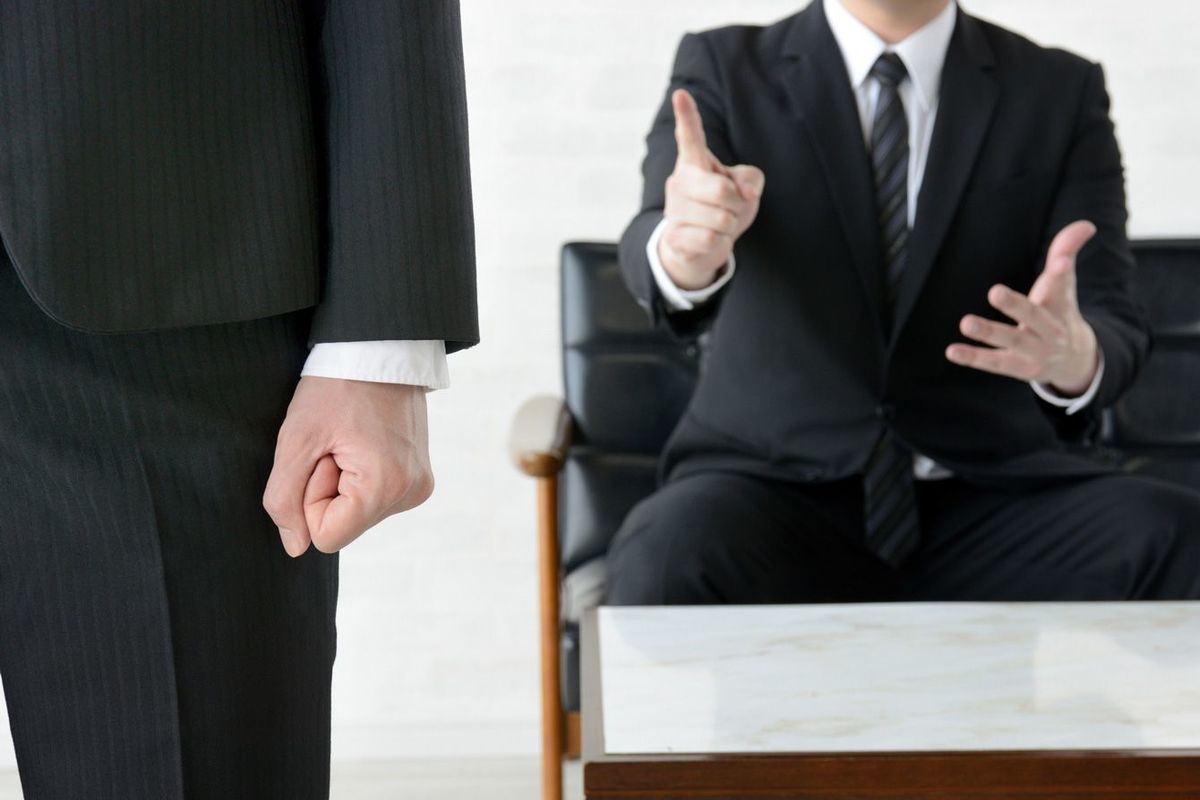 指をさして叱責する上司と拳を握るビジネスマン