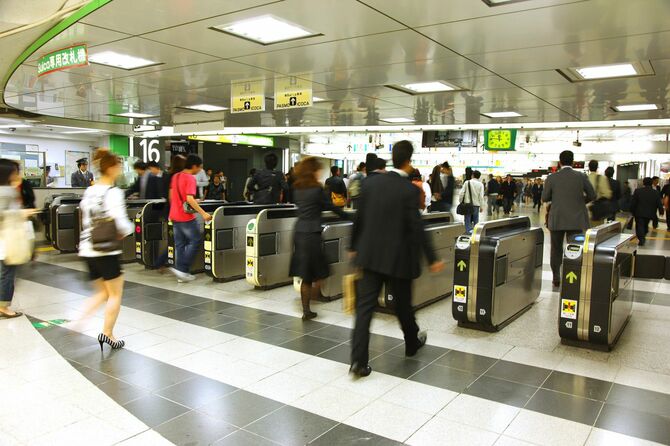 新宿駅の改札を歩く人
