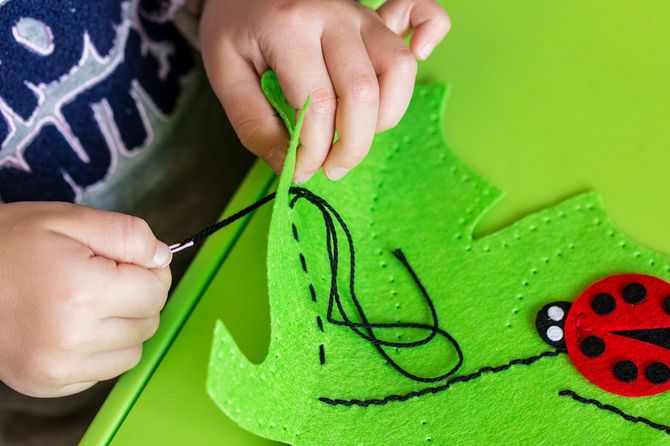 緑の葉と赤いテントウムシのフェルトの柔らかいおもちゃを作る子
