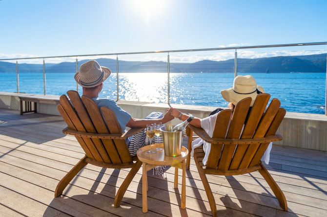 水上バンガローのデッキチェアでリラックスしてワインを飲むカップル