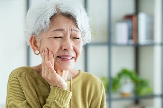 頬に手を当てて苦笑いする高齢女性