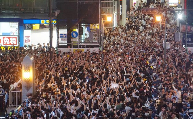 道頓堀川に架かる戎橋でスマホ画面を掲げ、阪神優勝の瞬間を待つファン＝2023年9月14日午後、大阪市