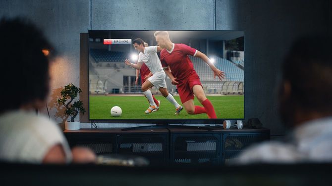 サッカーの試合のテレビ中継を見ているカップル
