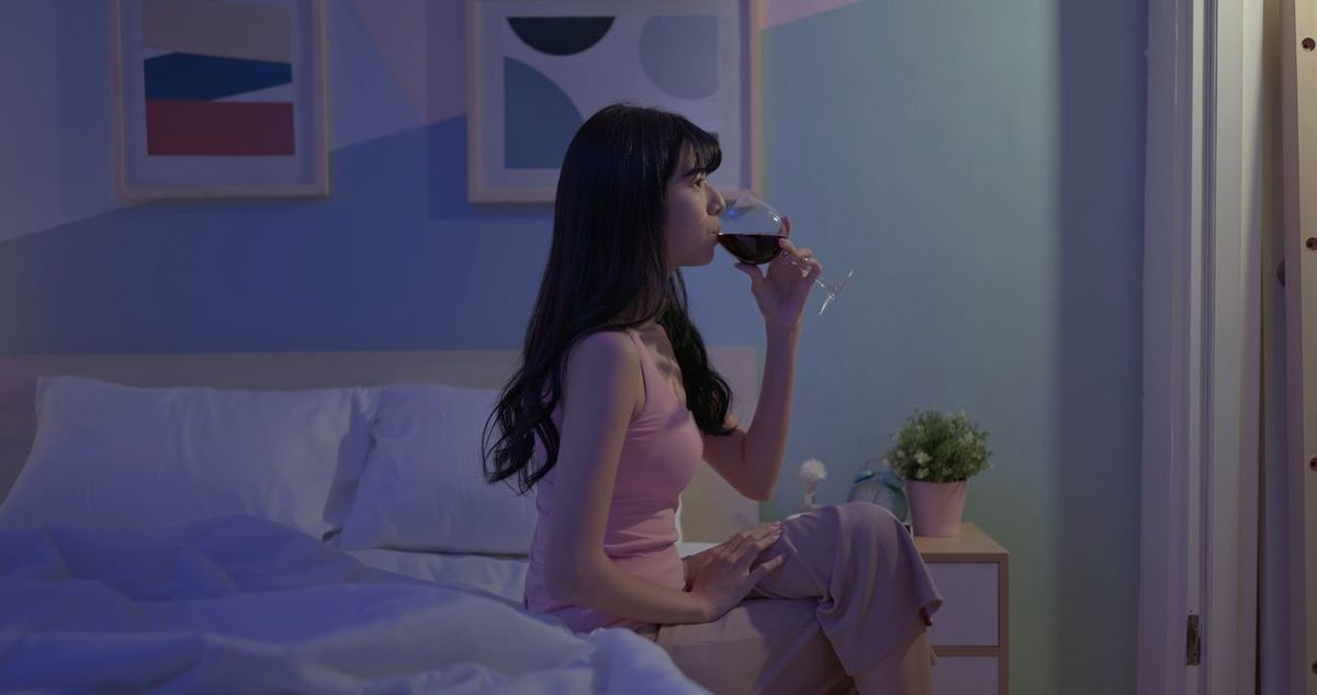 ベッドルームでワインを飲む女性