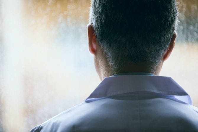 白衣を着た中年男性の後ろ姿