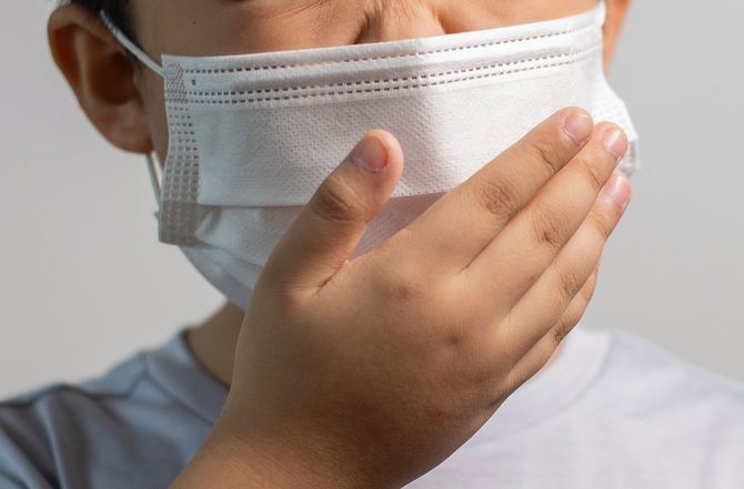 少年咳、灰色の背景に立ってフェイスマスクを着用