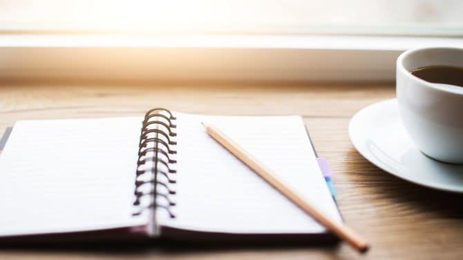 机の上にノートとコーヒー