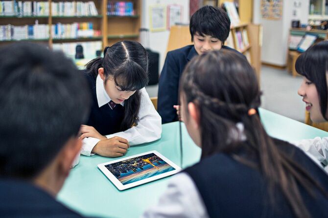 タブレットを見ながらグループで話し合いをする高校生