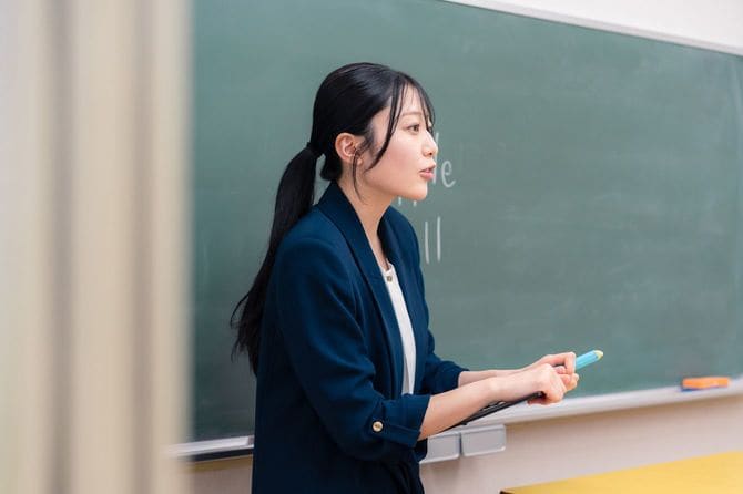 黒板の前に立ち、英語の授業をしている女性教師