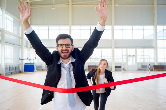 ゴールテープを切るバンザイをした男性