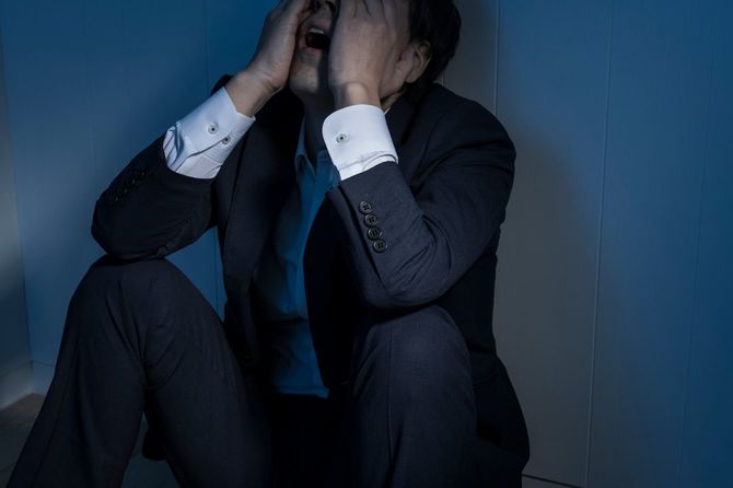 暗い部屋で途方に暮れる男性