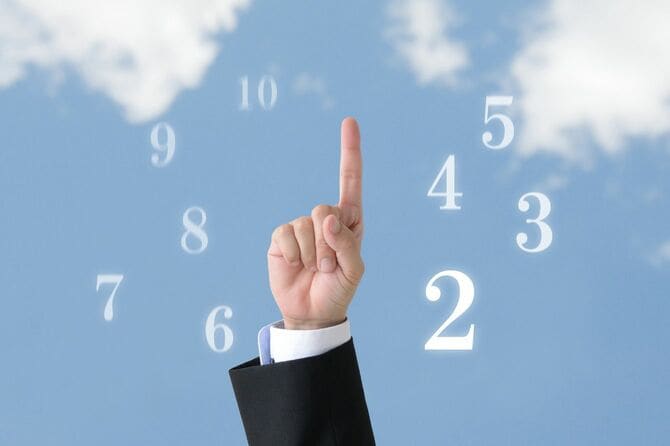 人差し指を立てたビジネスマンの手の周りにいくつもの数字が浮かんでいる