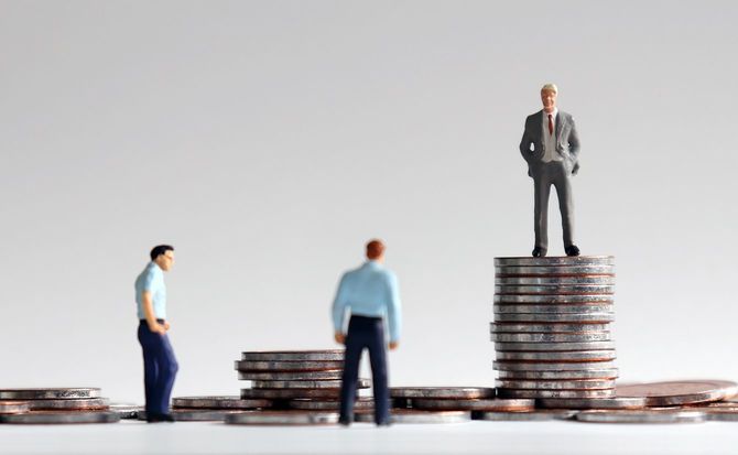 コインの山の上に立っているミニチュア人