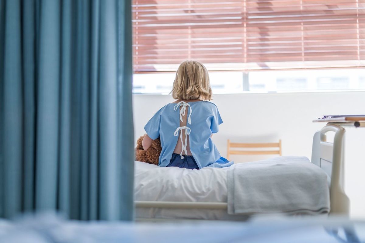 病院のベッドに座るガウンを着た子供