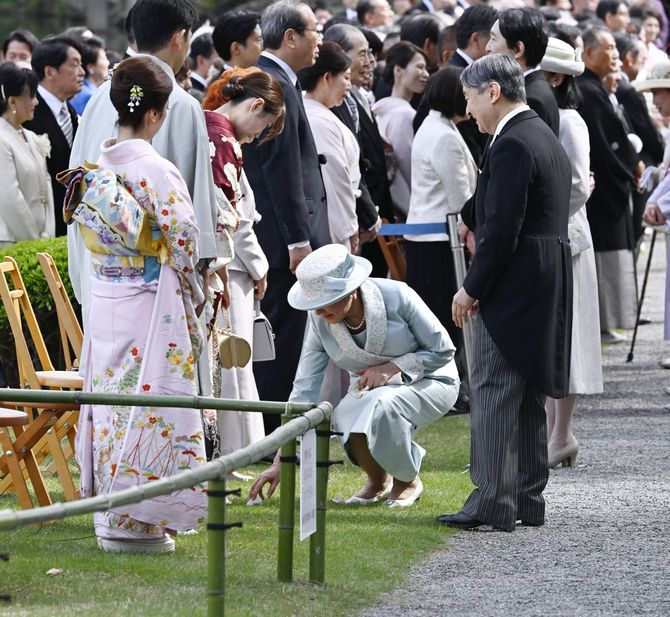 春の園遊会で、スノーボード女子の村瀬心椛選手（左手前から3人目）が付けていたマイクのカバーが落ち、かがんで拾われる皇后さま。2026年4月17日、東京・元赤坂の赤坂御苑